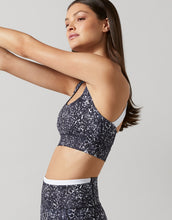 A model wearing a black geometric print sports bra and leggings on a white background.