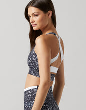 A woman wearing a black geometric print sports bra and leggings.
