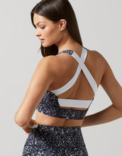 A model wearing a black geometric print sports bra and leggings.