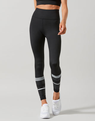 Person wearing black leggings with white stripes on a gray background
