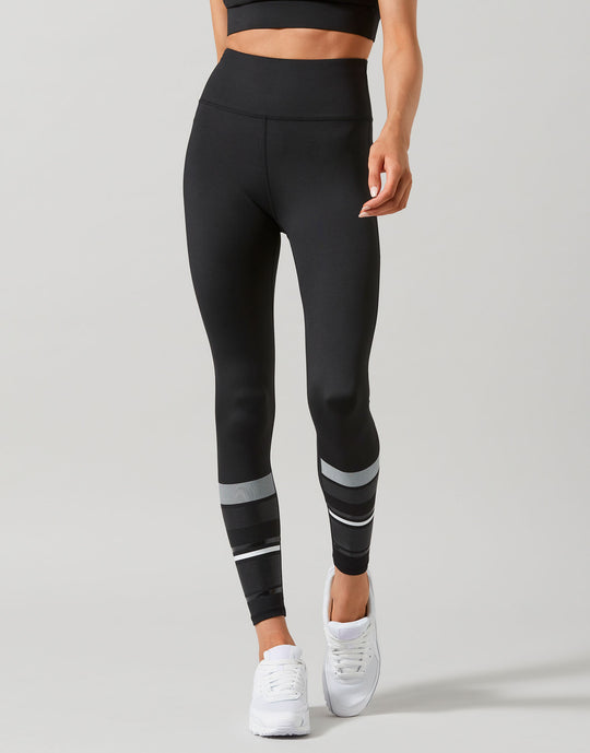 Person wearing black leggings with white stripes on a gray background