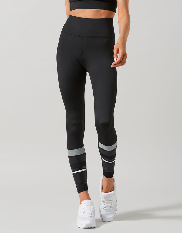 Person wearing black leggings with white stripes on a gray background