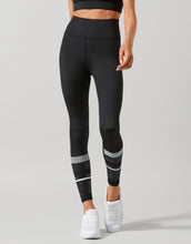 Person wearing black leggings with white stripes on a gray background