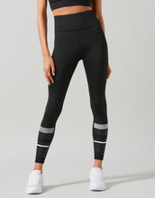 Person wearing black leggings with white stripes on a gray background