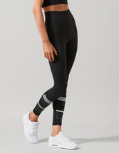 Person wearing black leggings with white stripes on a gray background