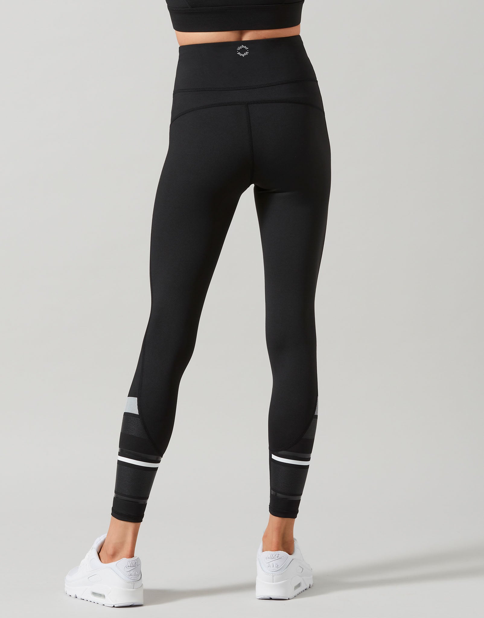 Black leggings with white accents worn by a person on a gray background