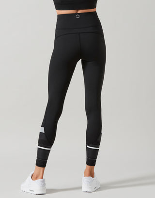 Black leggings with white accents worn by a person on a gray background