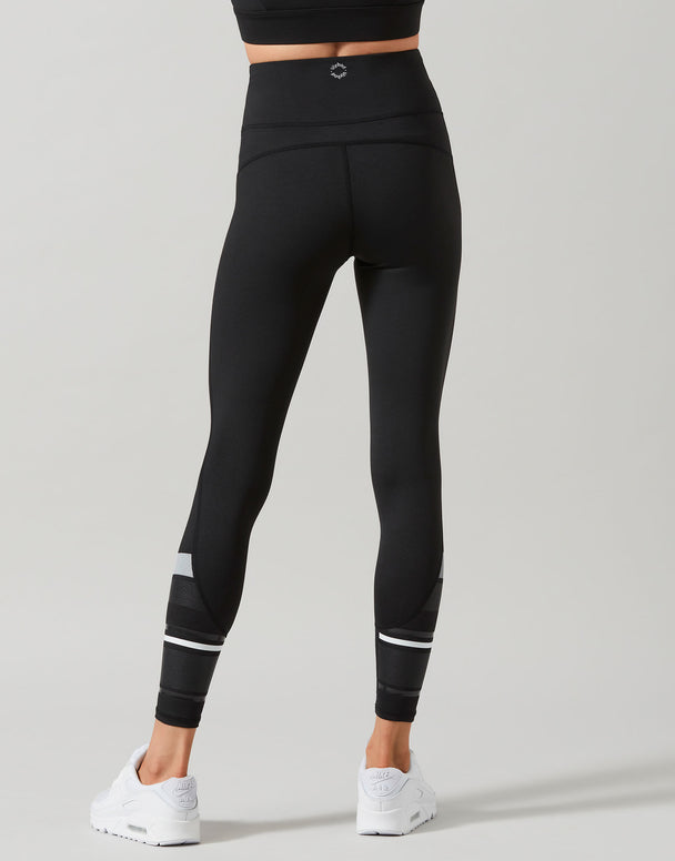 Black leggings with white accents worn by a person on a gray background