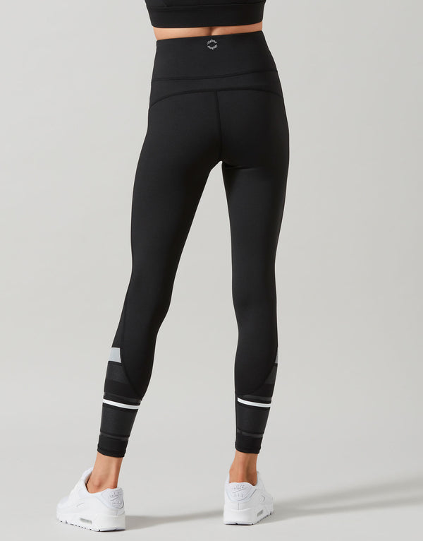 Black leggings with white accents worn by a person on a gray background