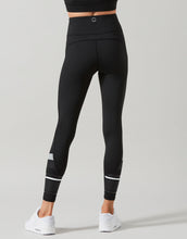 Black leggings with white accents worn by a person on a gray background