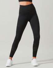 Person wearing black leggings with white sneakers on a light gray background