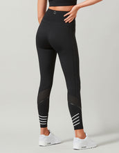 Black leggings with white stripes worn by a person on a gray background