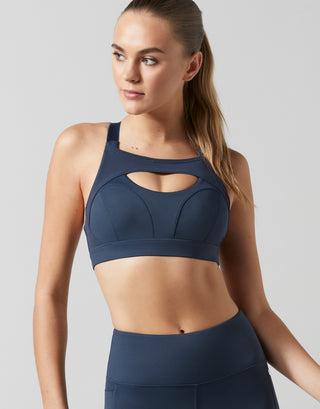 Woman wearing a navy blue sports bra and leggings on a light gray background