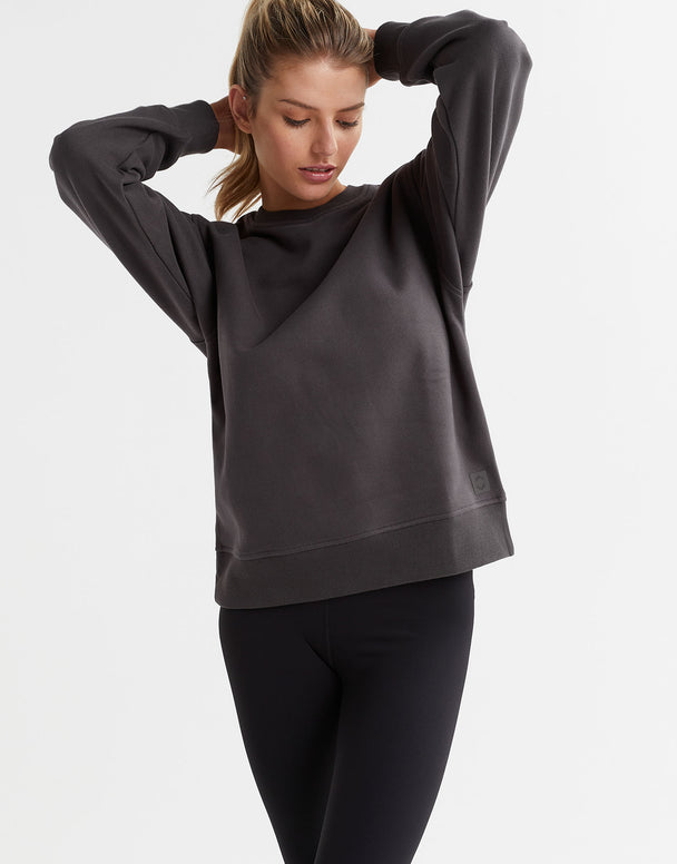 A female model wearing a gray Lilybod Montana fleece crew sweater, which is designed with a crew neck and long sleeves.