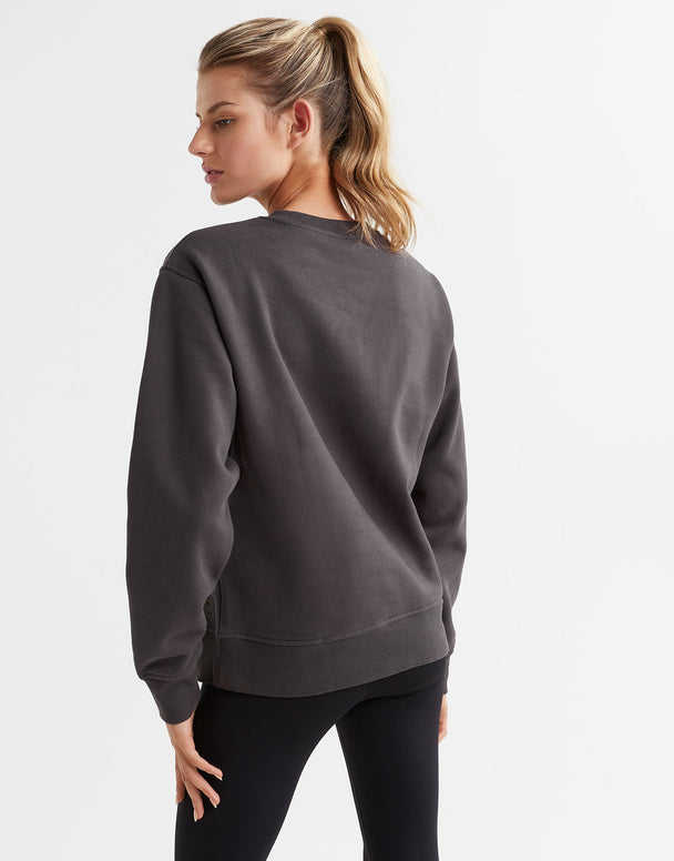 A female model wearing a gray Lilybod Montana fleece crew sweater, which is designed with a crew neck and long sleeves with black leggings.