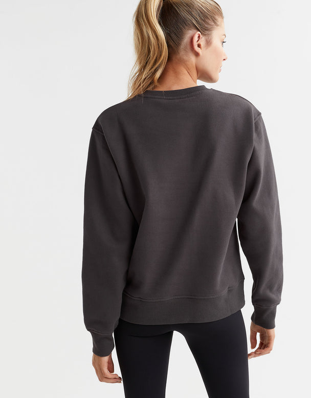 A  model wearing a gray Lilybod Montana fleece crew sweater, which is designed with a crew neck and long sleeves.