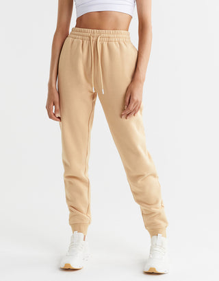Beige jogger pants worn by a person on a white background