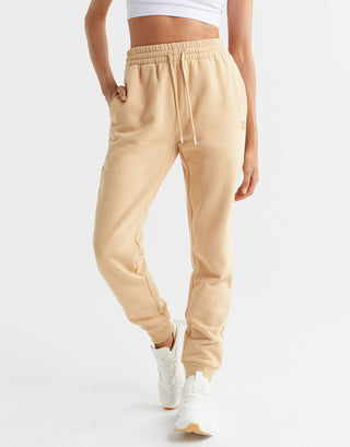 Beige sweatpants worn by a person on a white background