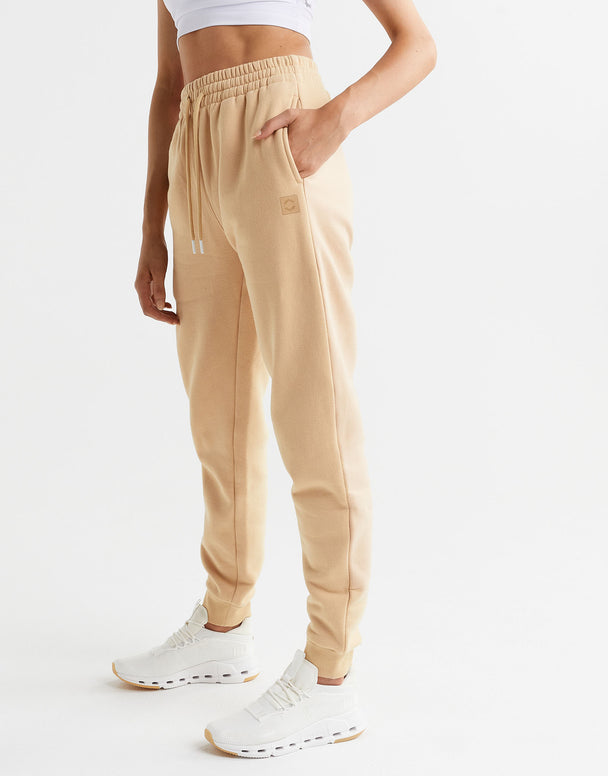 Beige sweatpants worn by a person on a white background