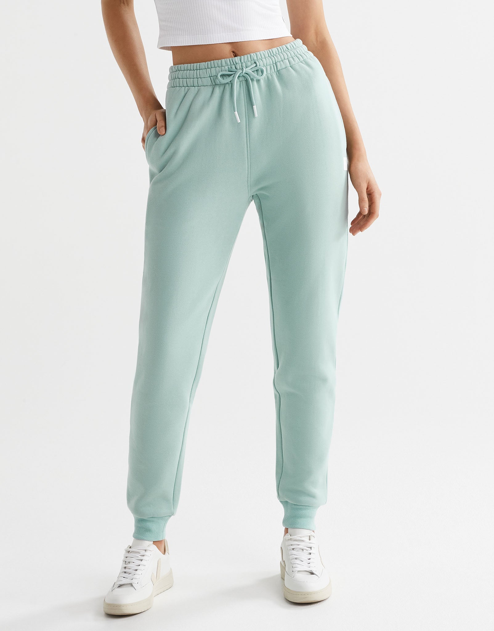 A pair of sage green fleece-lined slim leg sweatpants with a drawstring waistband, pockets, and lilybod accent details.