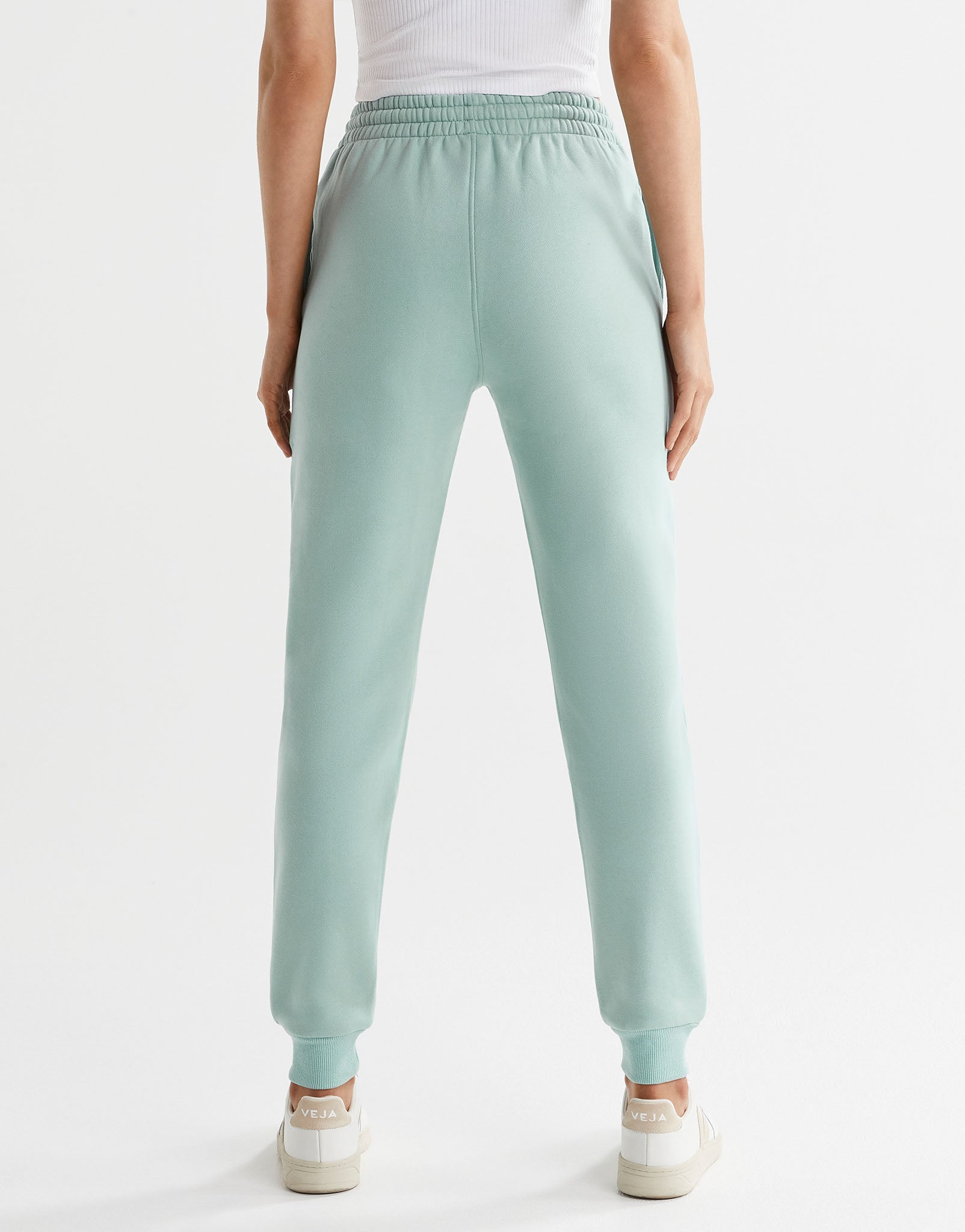 A pair of sage green fleece-lined slim leg sweatpants with a drawstring waistband, pockets, and lilybod logo.