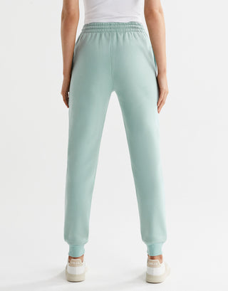 A pair of sage green fleece-lined slim leg sweatpants with a drawstring waistband, pockets, and lilybod logo.
