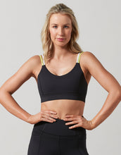 Woman wearing a black sports bra and leggings on a gray background