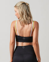 Woman wearing a black sports bra and leggings with a gray background