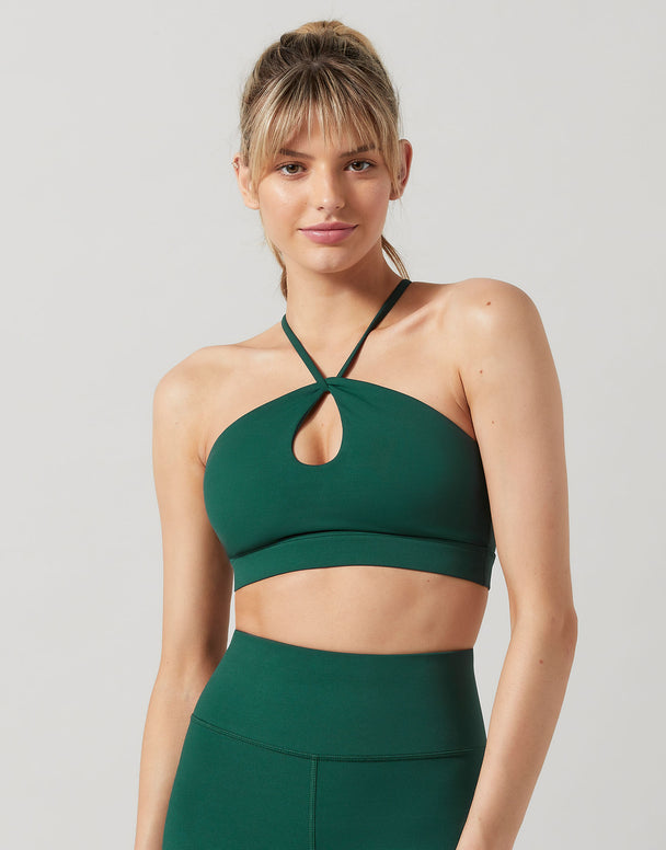 Woman wearing a green sports bra and leggings on a light gray background