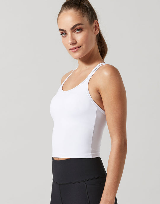 A woman wearing a white activewear top and black leggings.