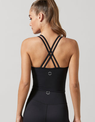 A woman wearing a black strappy activewear top and leggings.