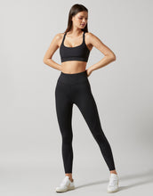 Woman wearing a black athletic outfit on a light gray background