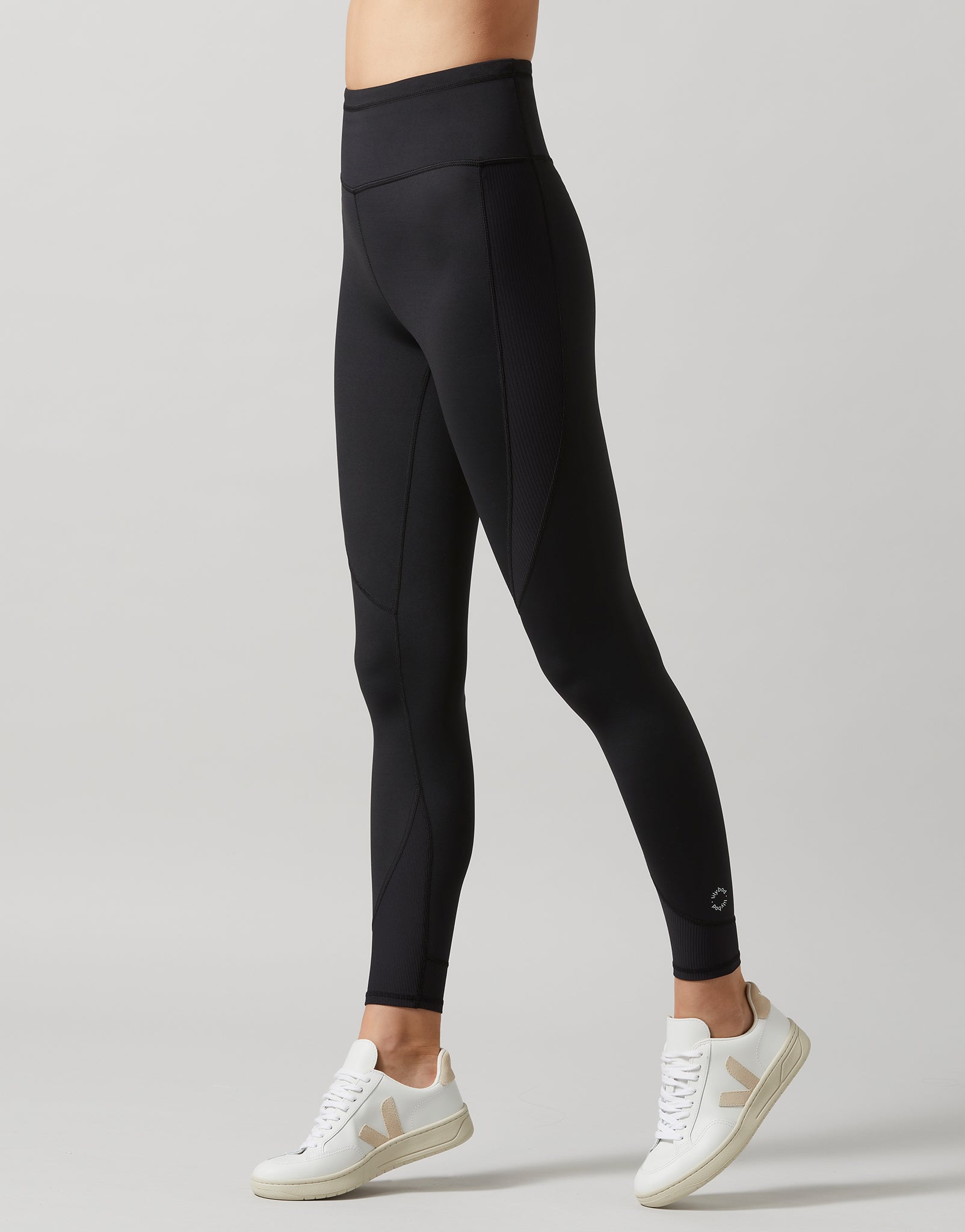Person wearing black leggings with a gray background