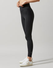 Person wearing black leggings with a plain background