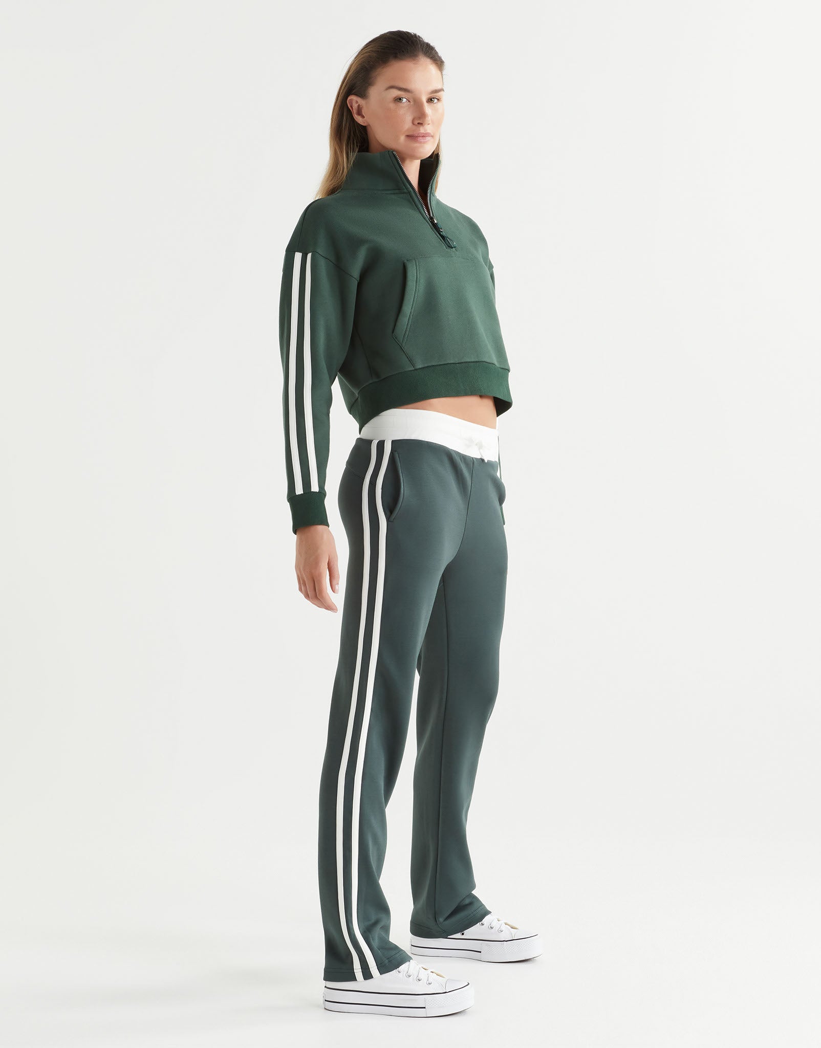 Person wearing a green tracksuit with white stripes on a white background