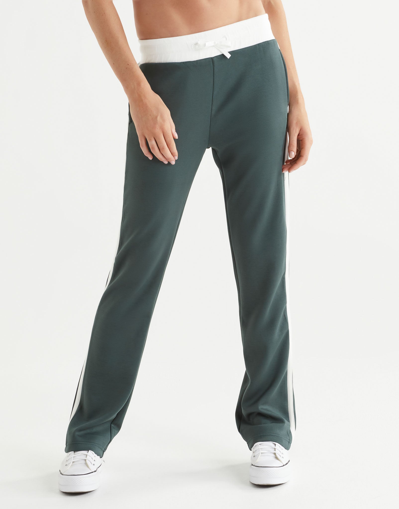Green track pants with white stripes on a white background