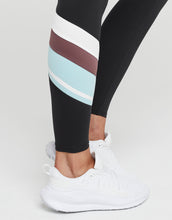 Black leggings with colorful stripes worn by a person on a white background
