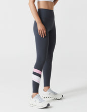 Person wearing dark gray leggings with pink and white striped socks on a light gray background