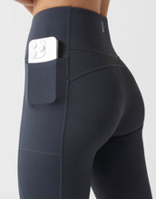 Black leggings with a pocket holding a phone on a light gray background
