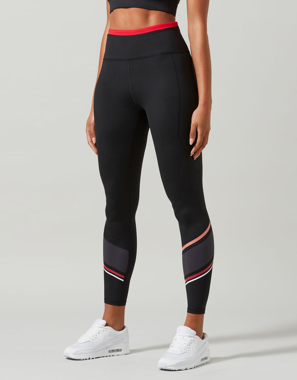 Black leggings with red and white accents worn by a person on a gray background