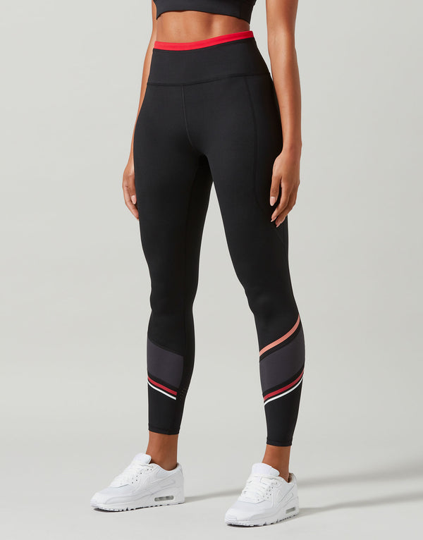 Black leggings with red and white accents worn by a person on a gray background