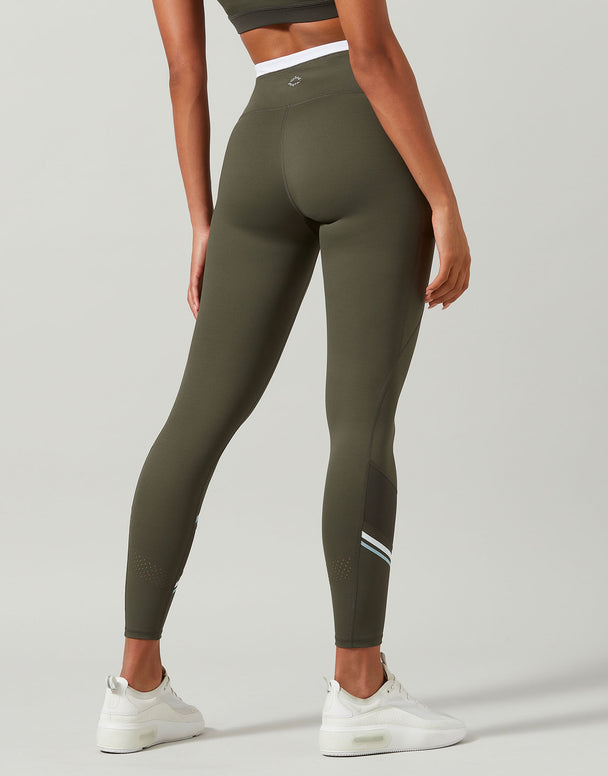 Person wearing olive green leggings with a white logo on a gray background
