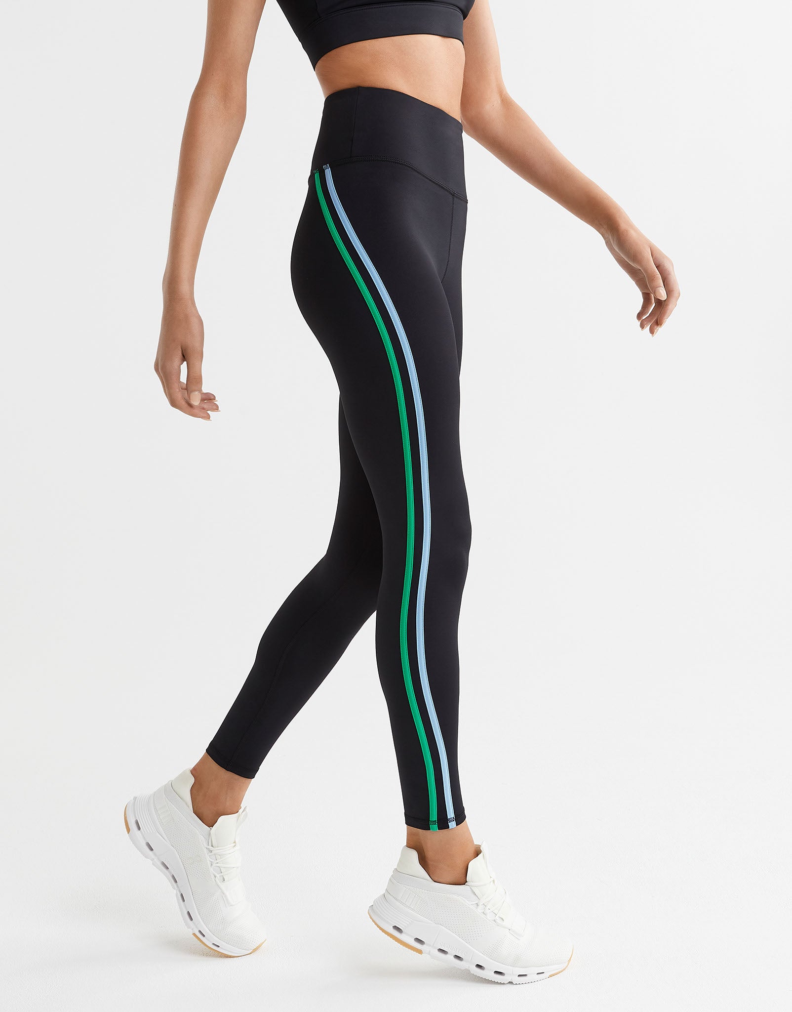 Black leggings with green and white stripes worn by a person on a light gray background