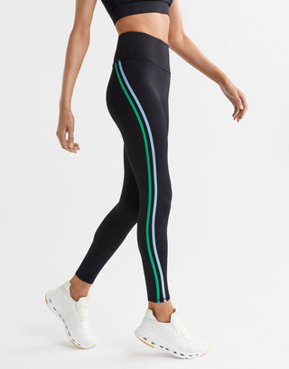 Black leggings with green and white stripes worn by a person on a light gray background