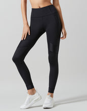 Person wearing black leggings and white sneakers on a light gray background