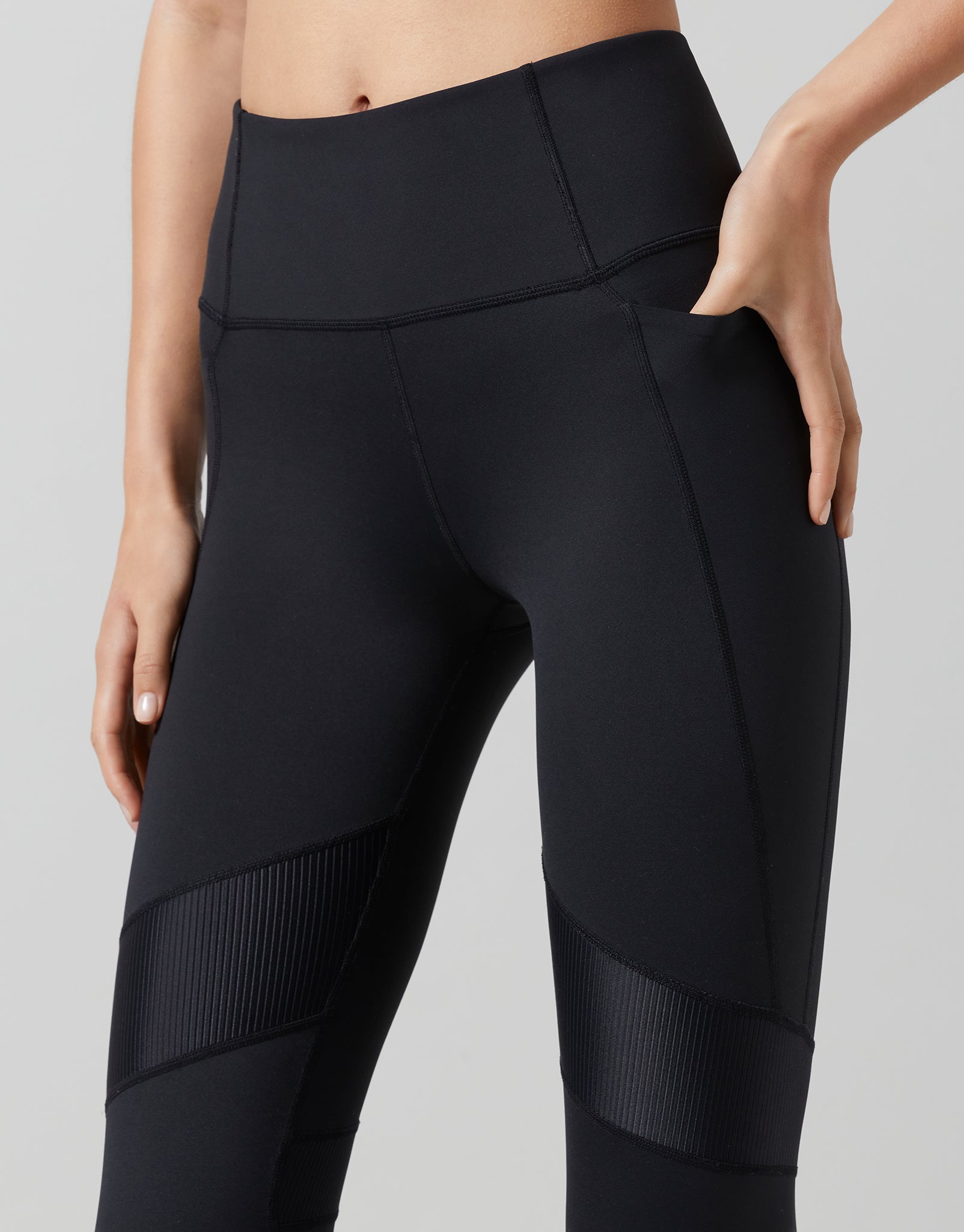 Black leggings with textured panels on a gray background