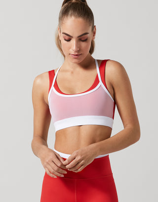 A woman wearing a red and white double layer sports bra with red leggings.