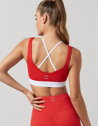 A rear view of a woman wearing a red and white double layer sports bra with red leggings.