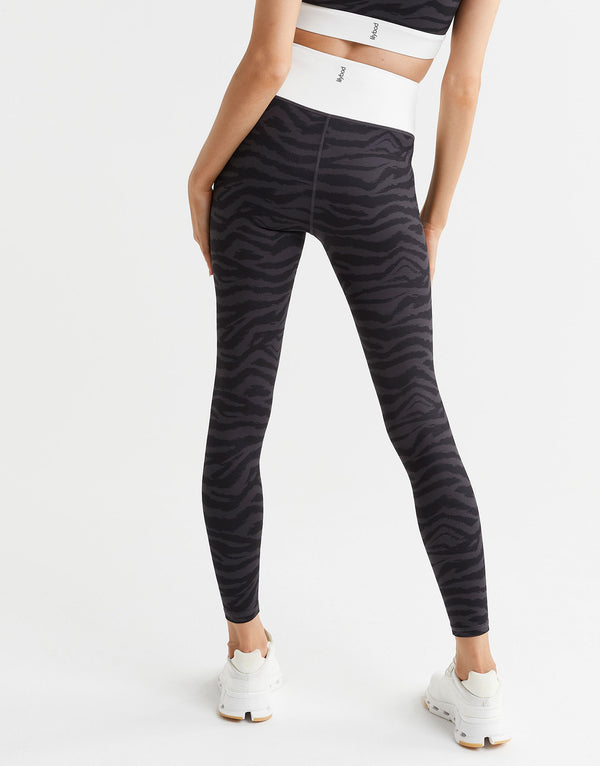 Person wearing black zebra-striped leggings on a white background