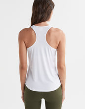 Woman wearing a white tank top and green leggings on a light gray background